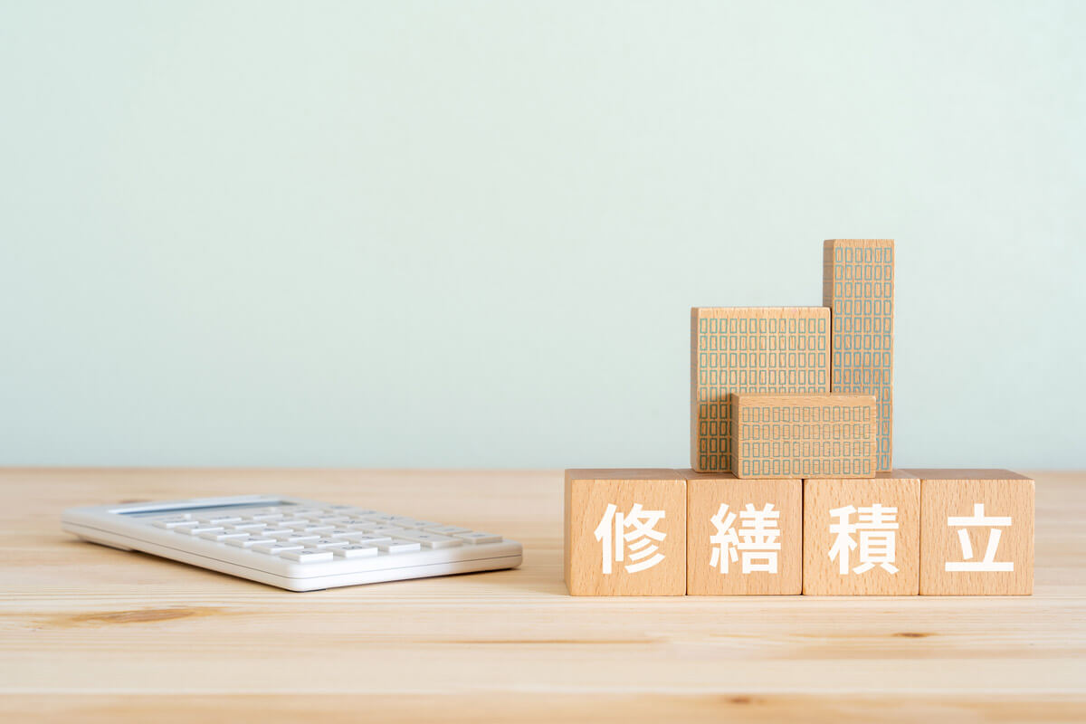 修繕積立と書かれたブロック、不動産の模型、電卓